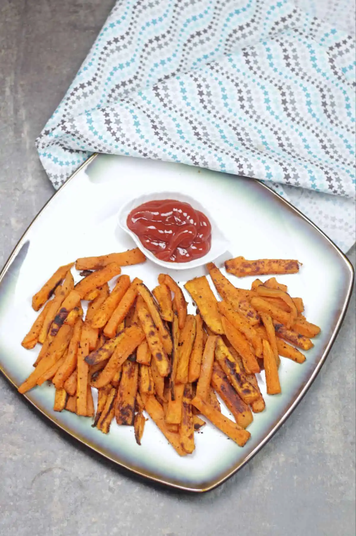 sweet potato fries in a plate with ketchup on side.