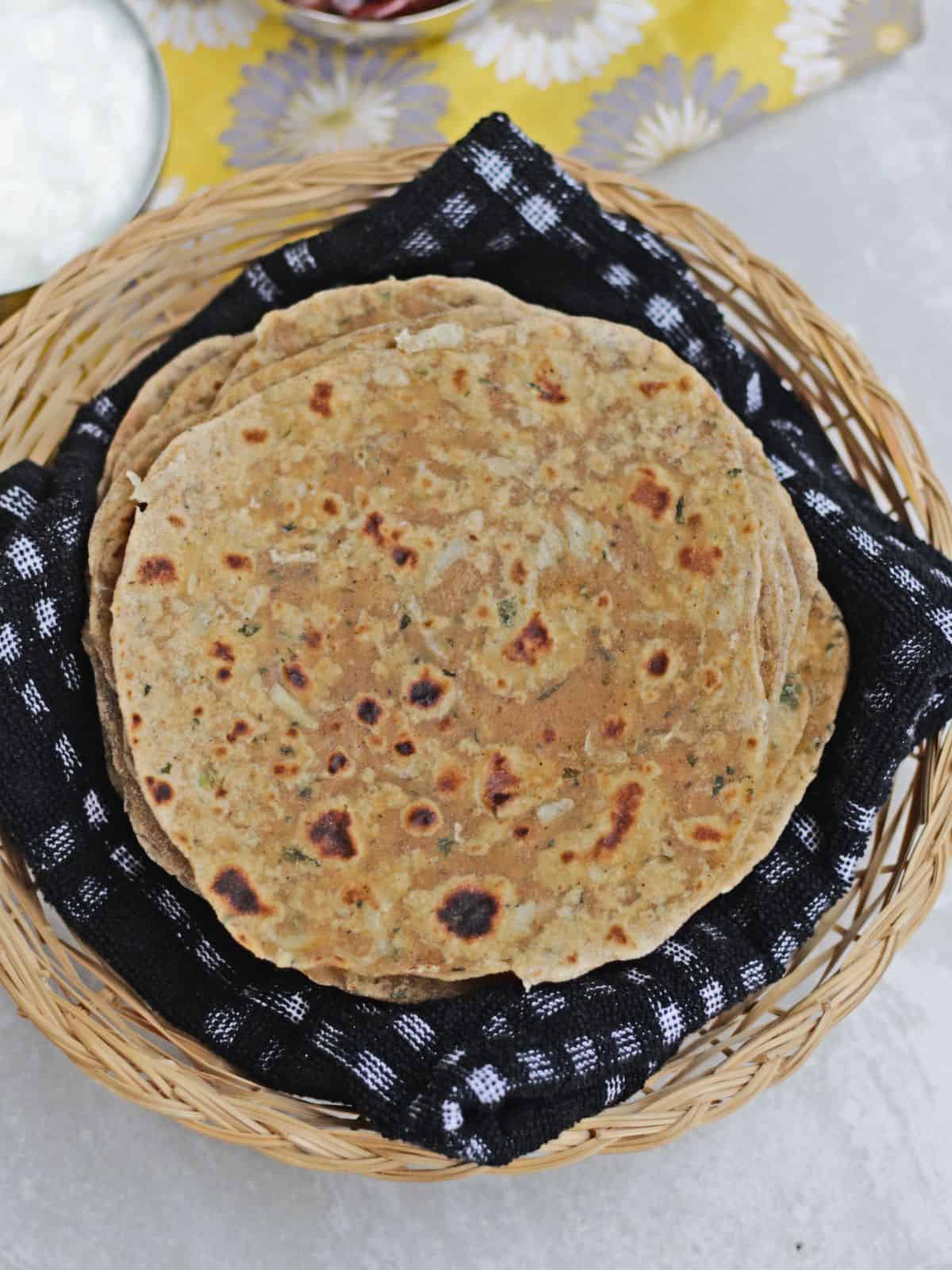 top view of radish paratha in a basket lined with black cloth.