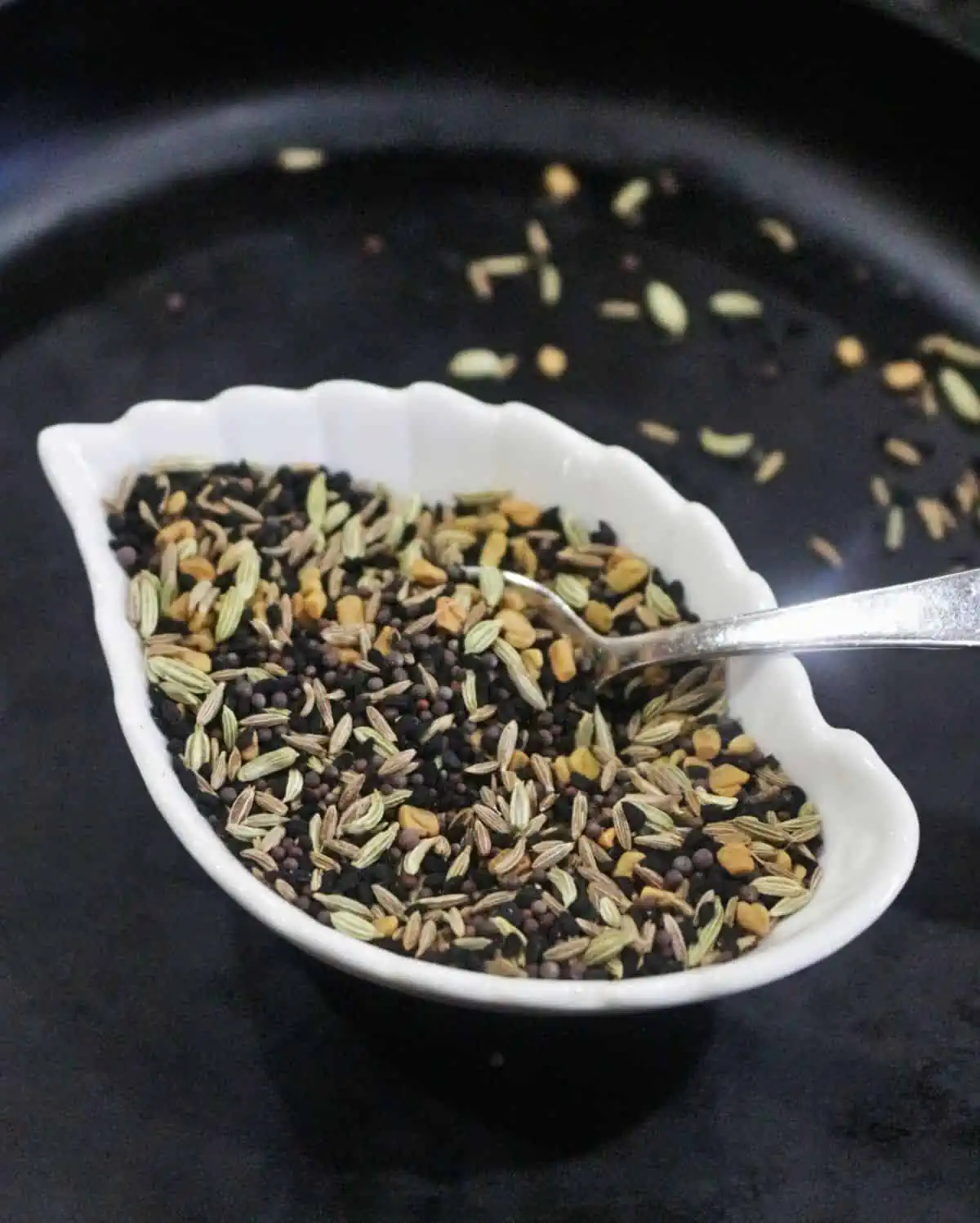 Panch phoran spice blend in a white bowl.