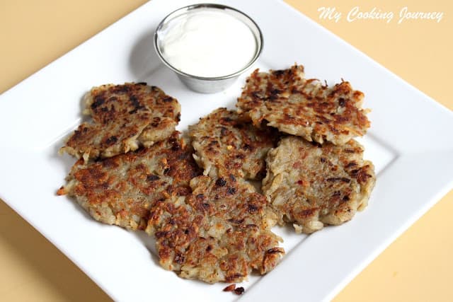 Latkes in a plate with sour cream on the side.