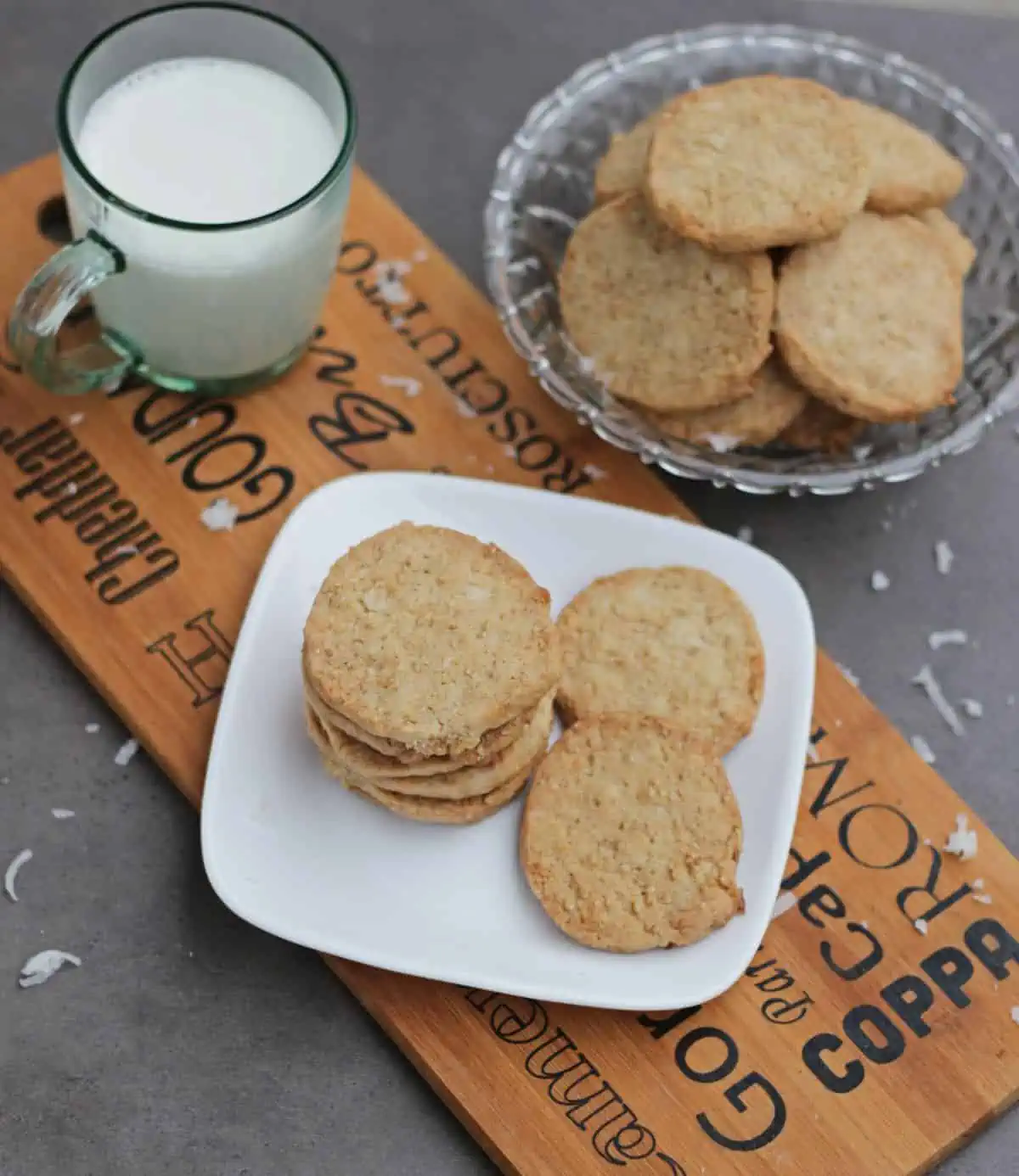 Coconut cookies in a plate and bowl with milk on the side.