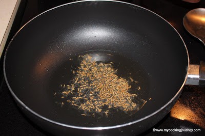 Frying cumin seeds in oil. 