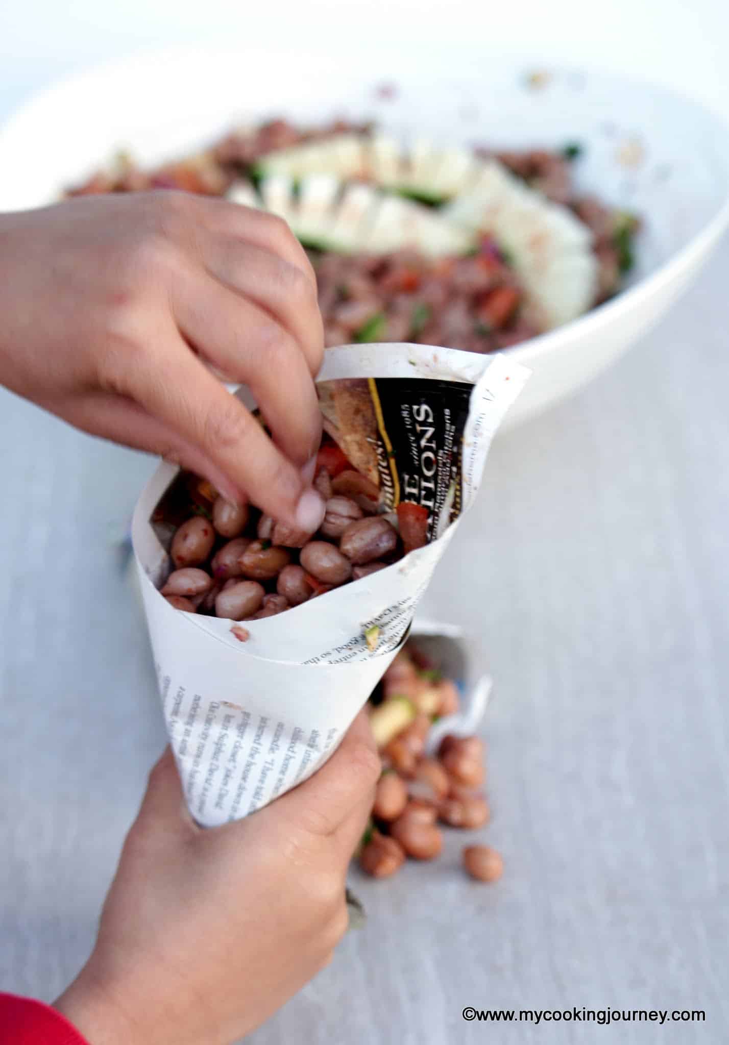 Masala Peanuts wrapped in a paper cone held in hand