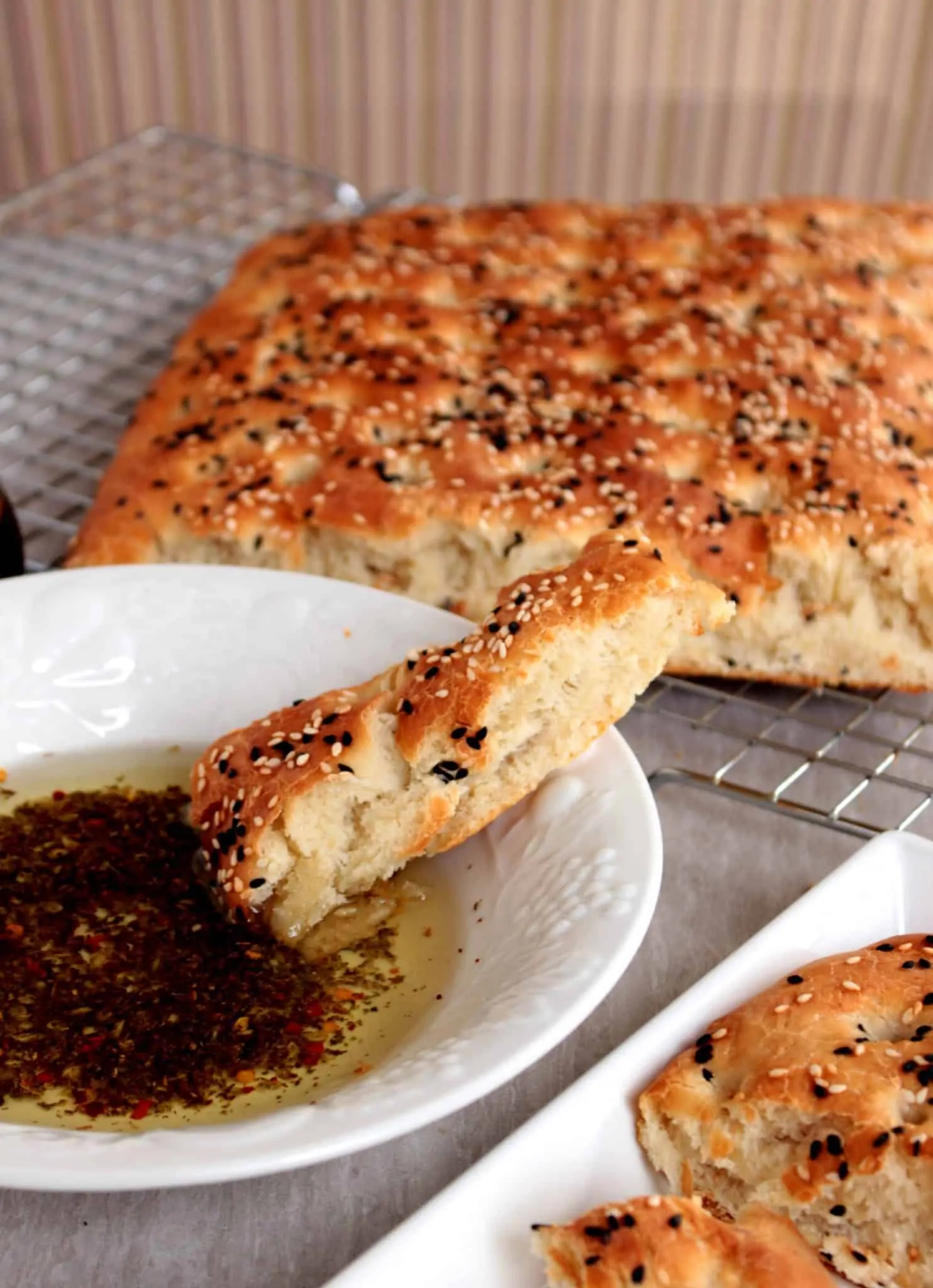 A slice of lagana flatbread dipped in dipping oil. 