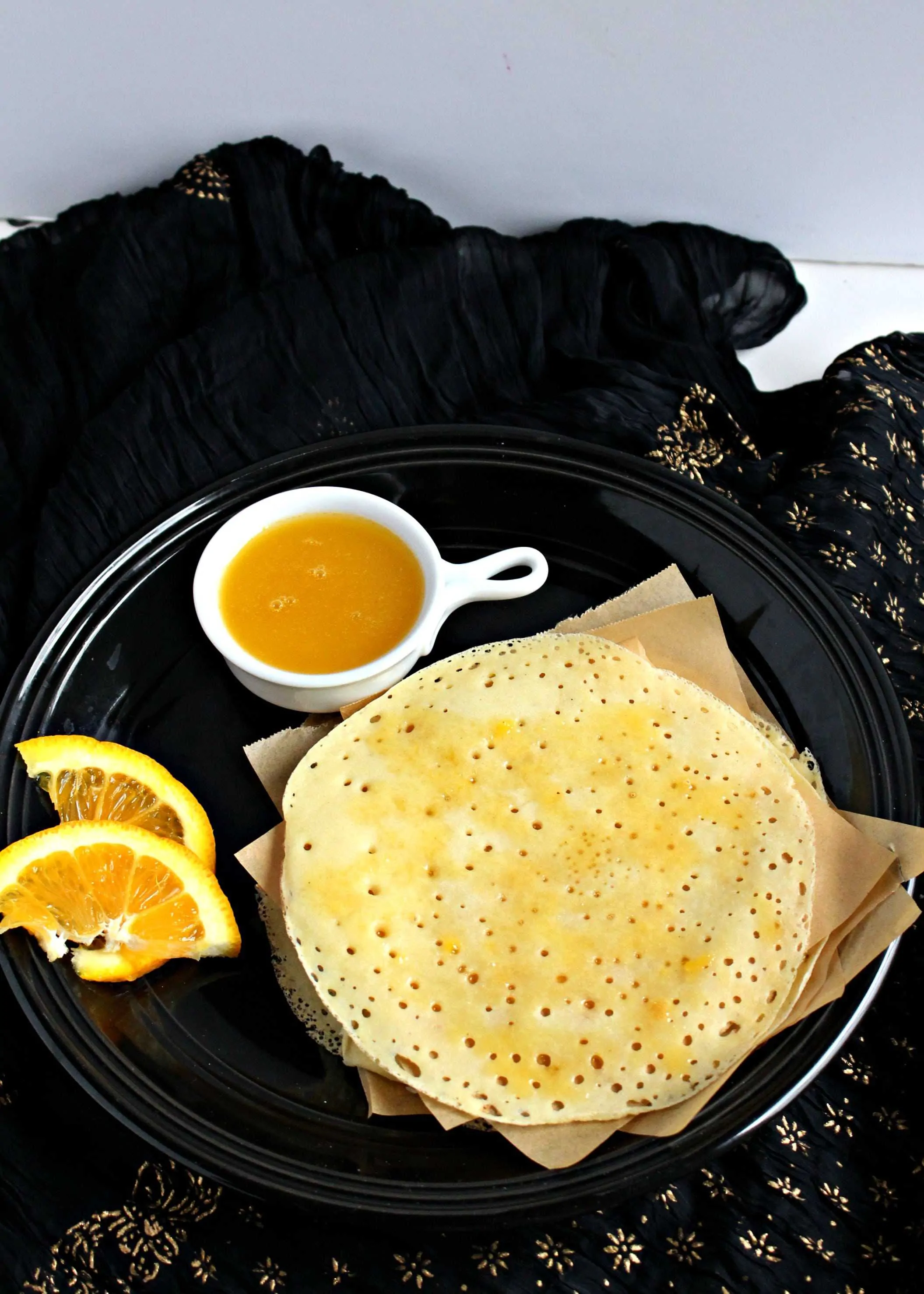 Baghrir with Orange Butter Sauce in a black plate 