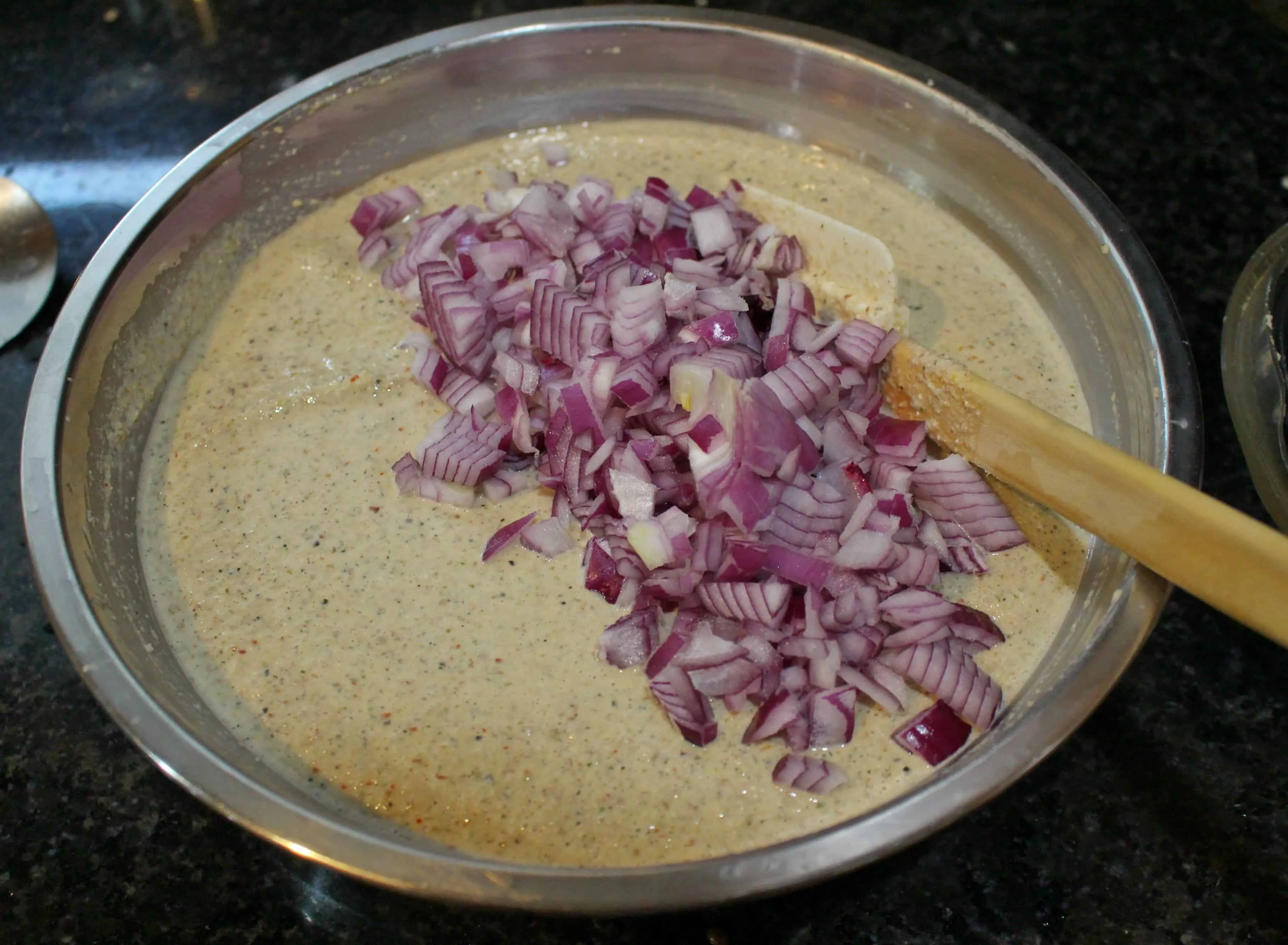 adai dosai batter with chopped red onions on top