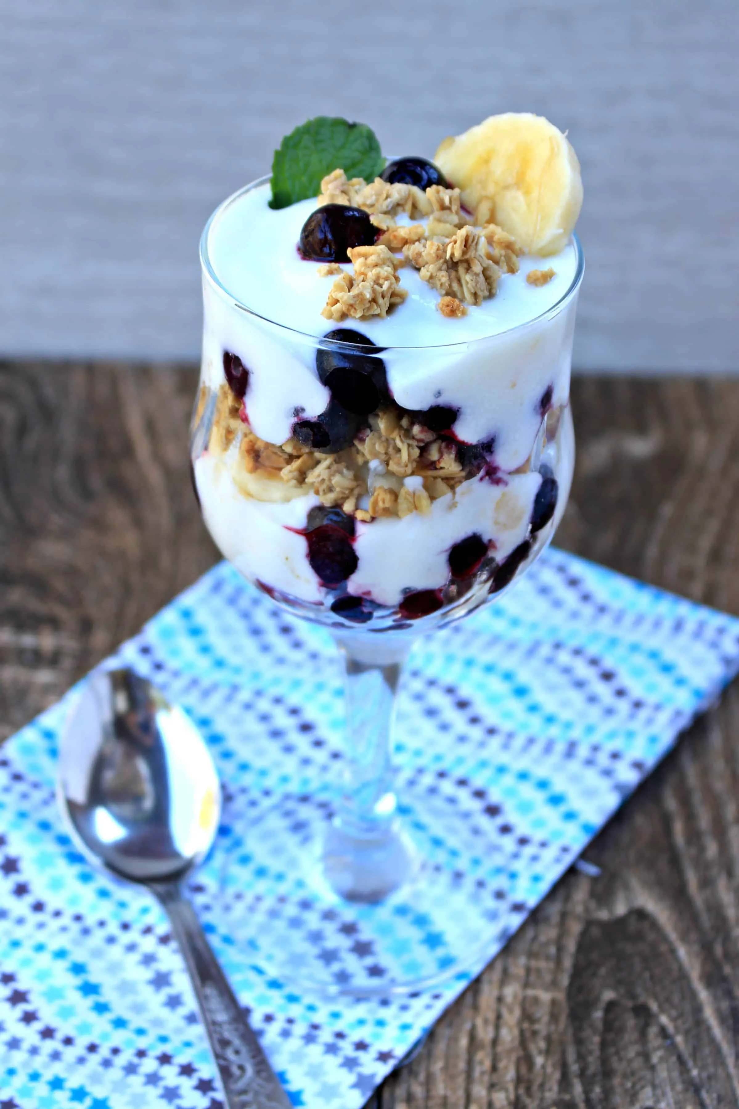 Yogurt Blueberry Banana Granola Parfait in a glass with spoon on the side