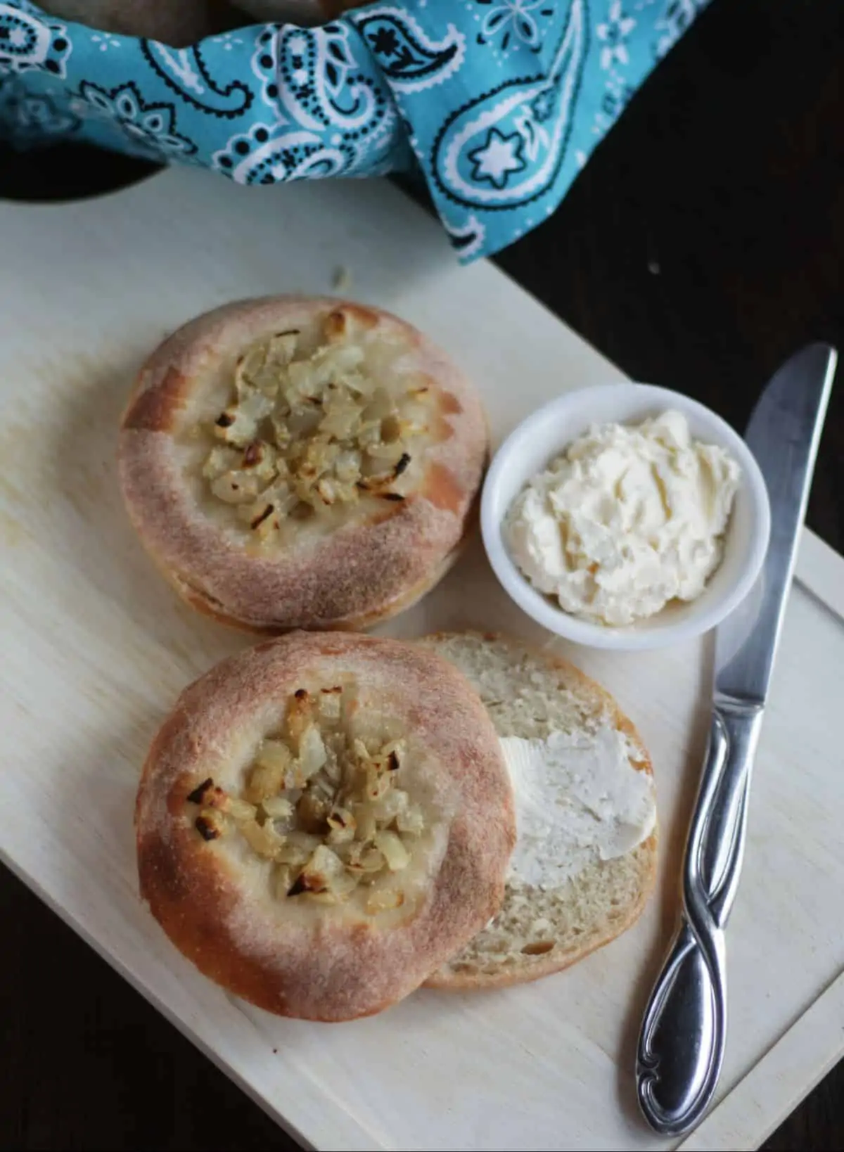 Bialy in wooden platter sliced and smeared with butter.