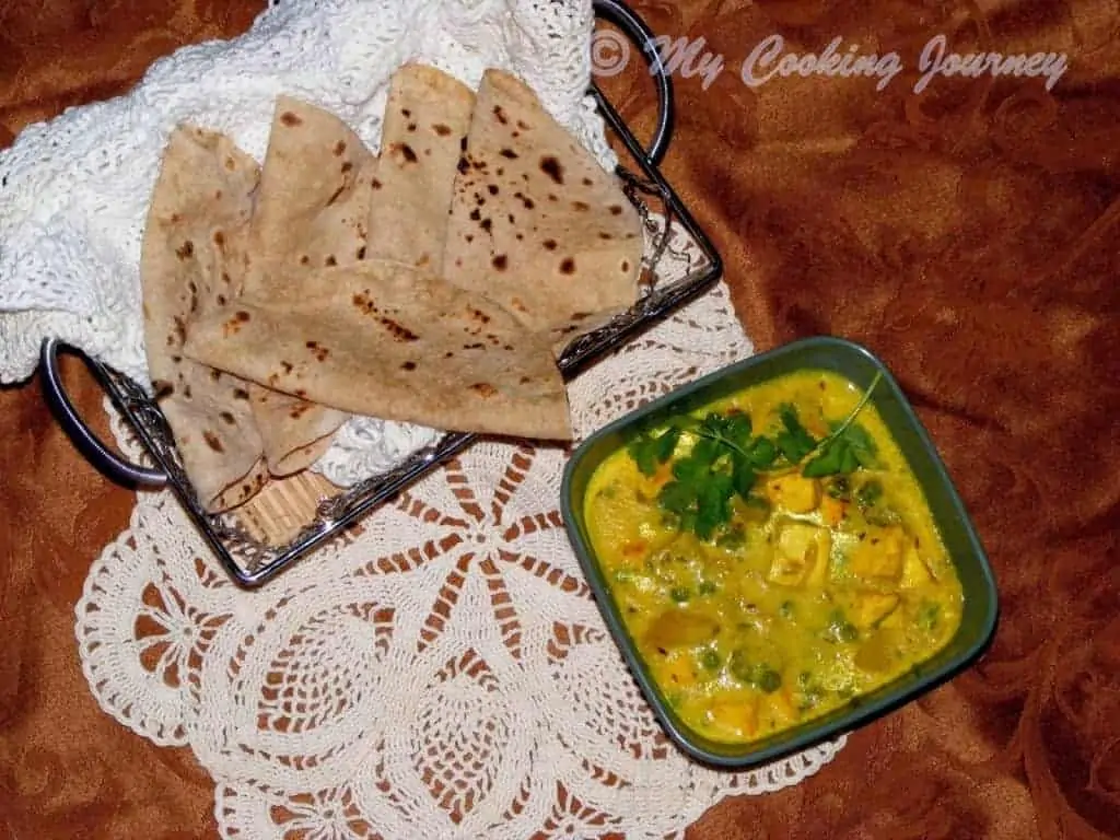 Sana Thongba garnished with cilantro in a bowl with roti on the side.