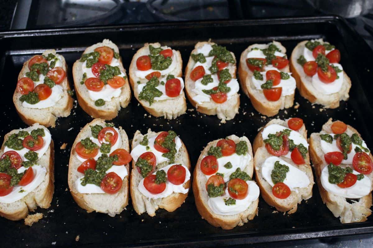 bread slices topped with tomato , cheese and basil pesto