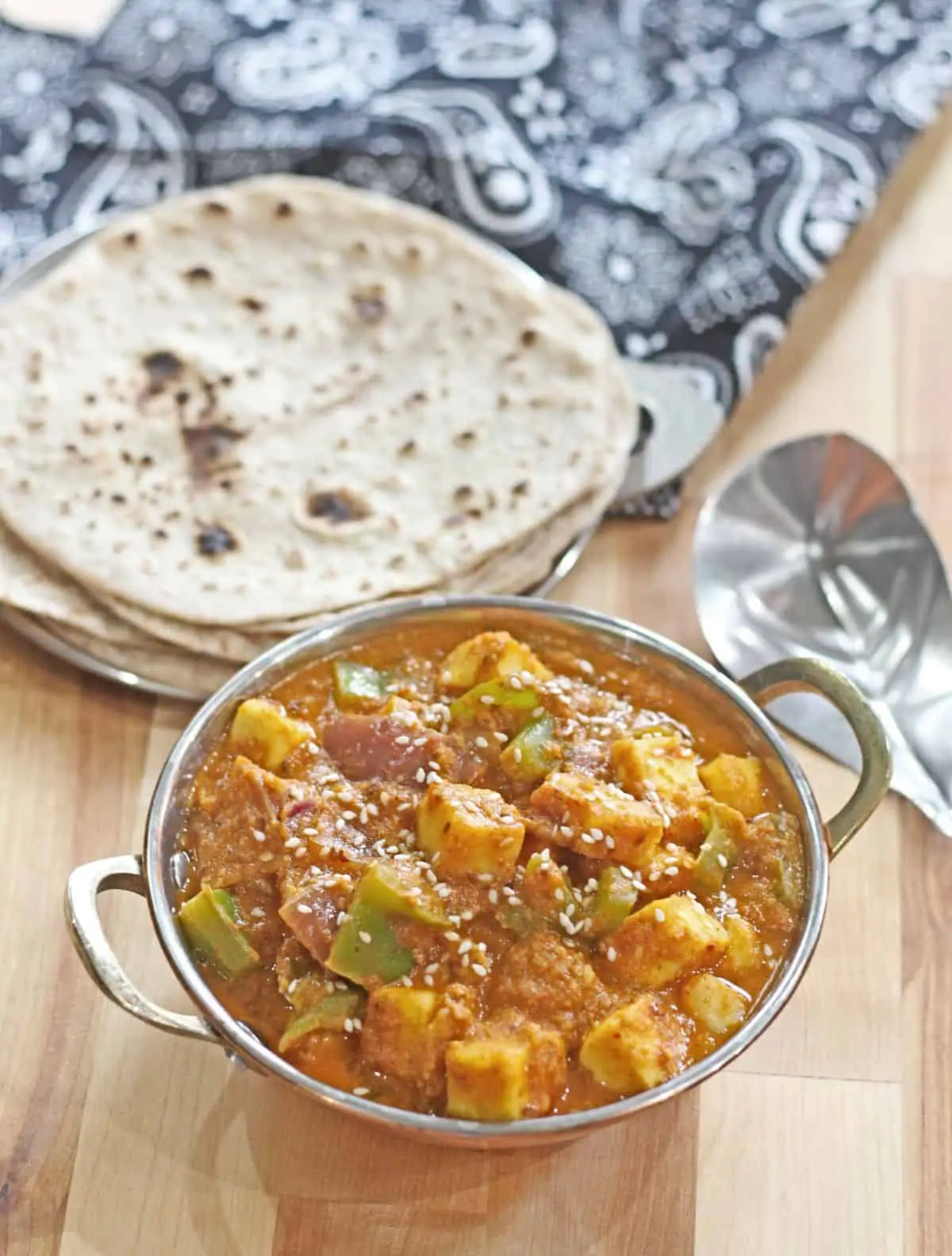Paneer hyderabadi curry in a bowl with roti in the background