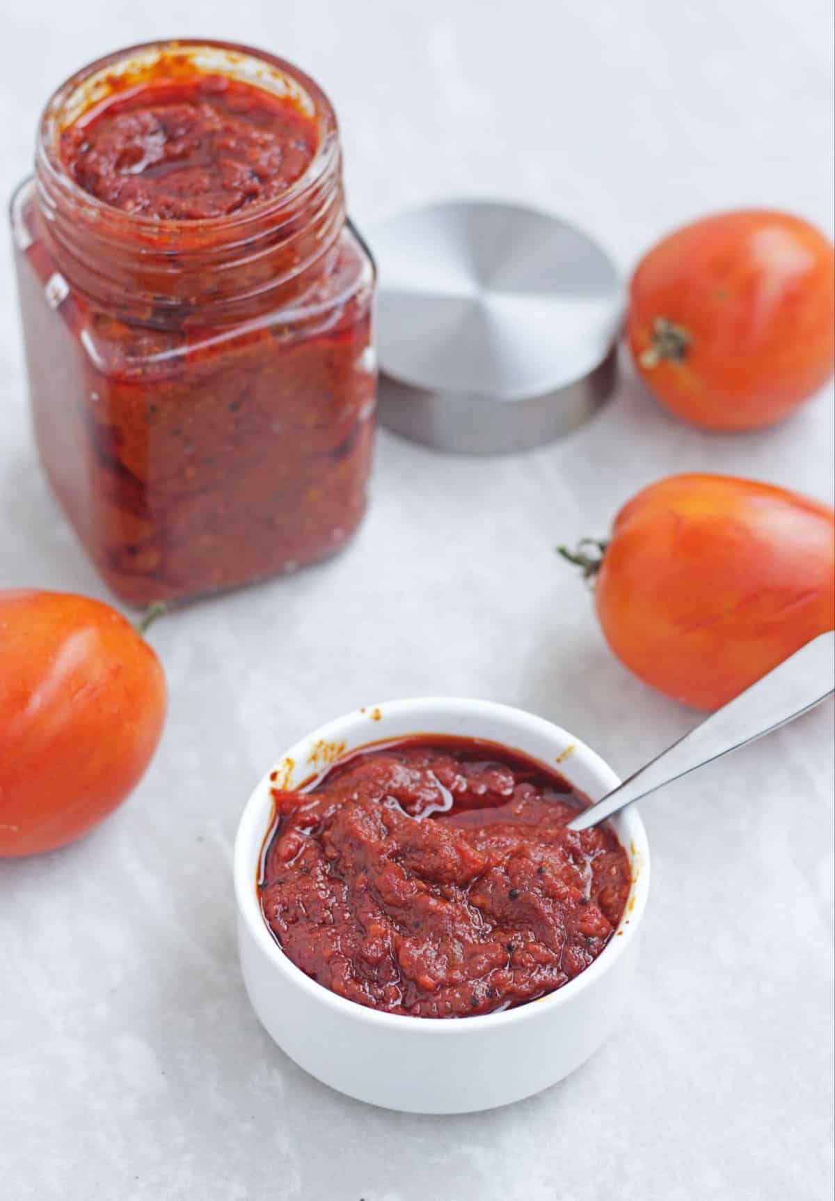 tomato pickle in a bowl with spoon and in a jar in the background