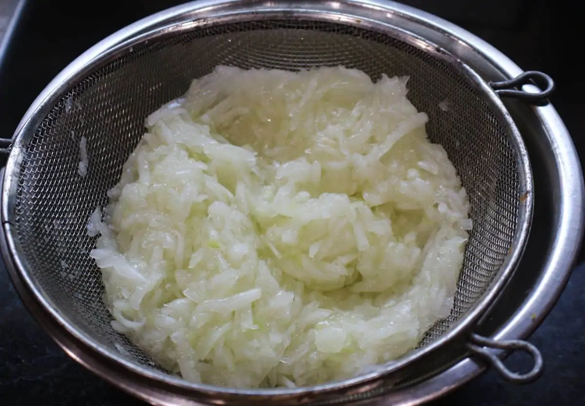 grated bottle gourd in a strainer