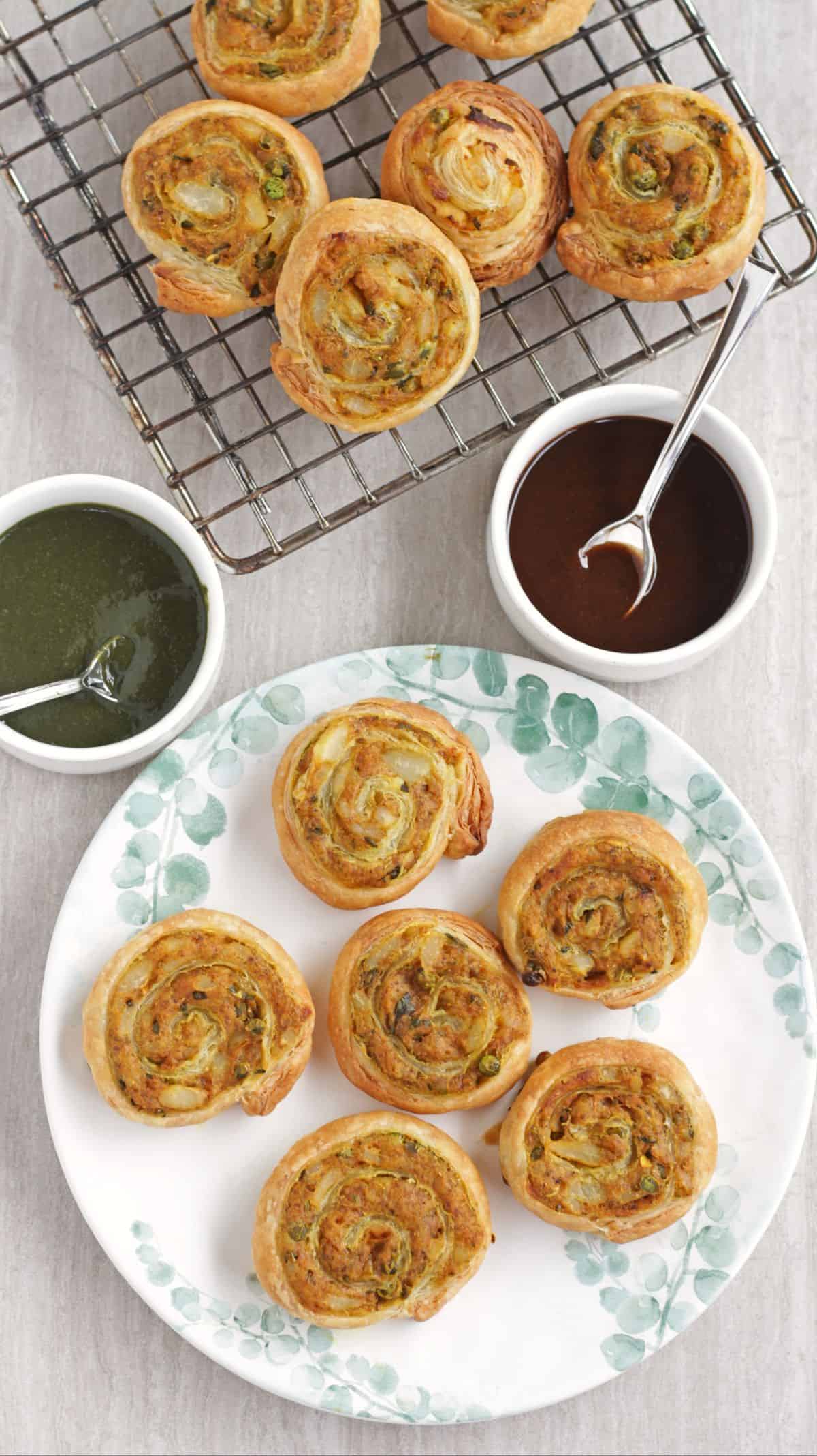Puff pastry samosa pinwheel in a white plate and on rack with chutney