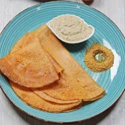 dosai on a blue plate with chutney and podi