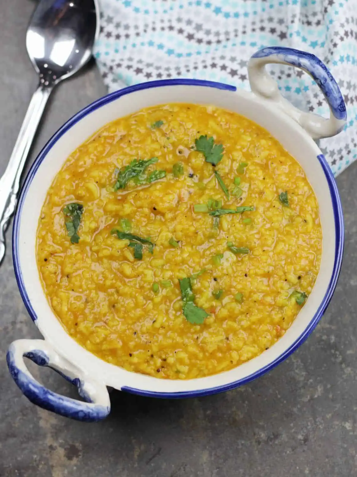 rasam rice in a bowl with spoon on the side.