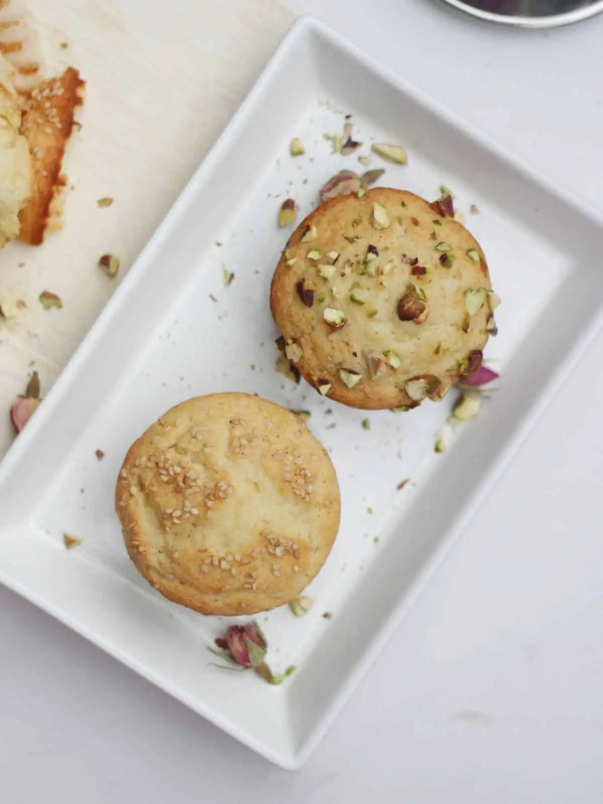 Top view of two muffins garnished with sesame seeds and pistachios.