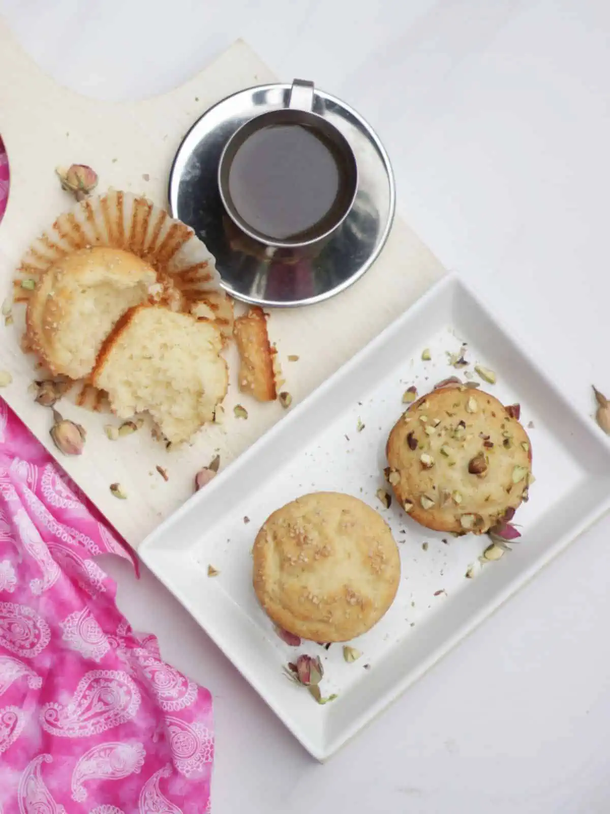 Muffins in a plate and one sliced open with coffee on side.