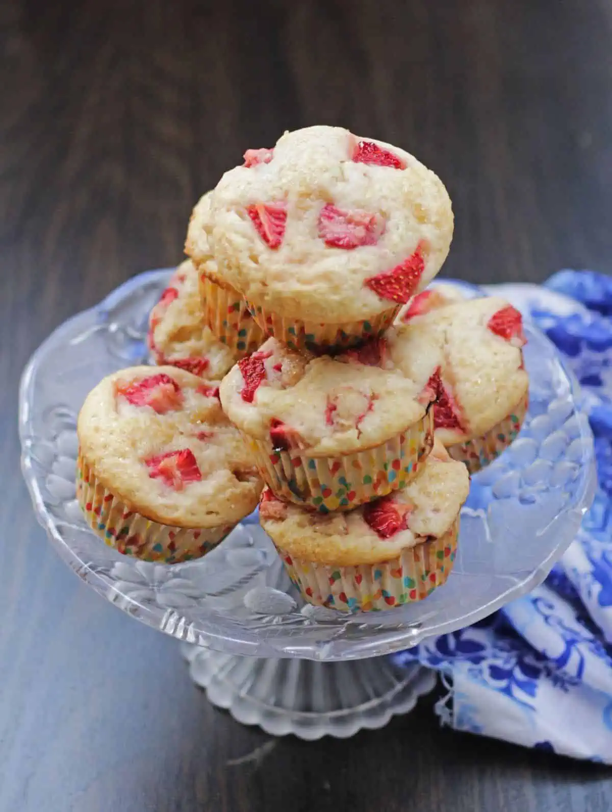 A stack of muffin with strawberries in a glass serving platter.