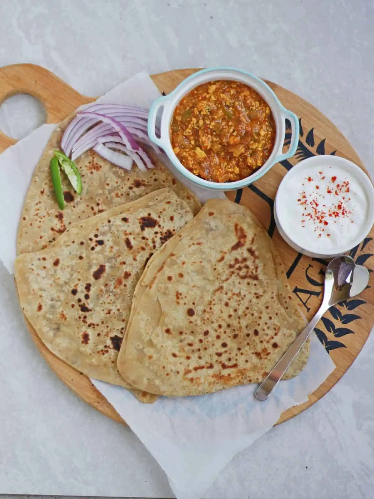 Top view of ajwain paratha in a plate with side.