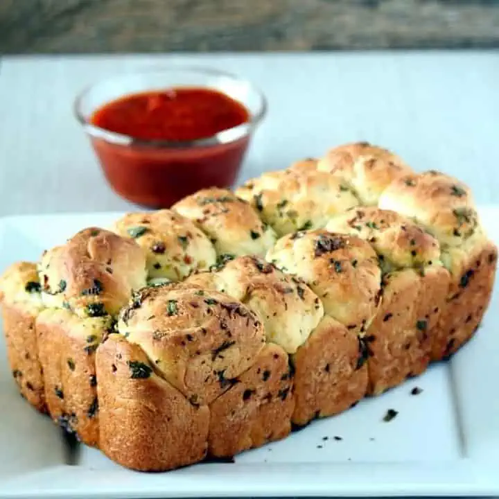 Pull Apart Garlic Bred in a white plate with dipping sauce on the side - Featured Image